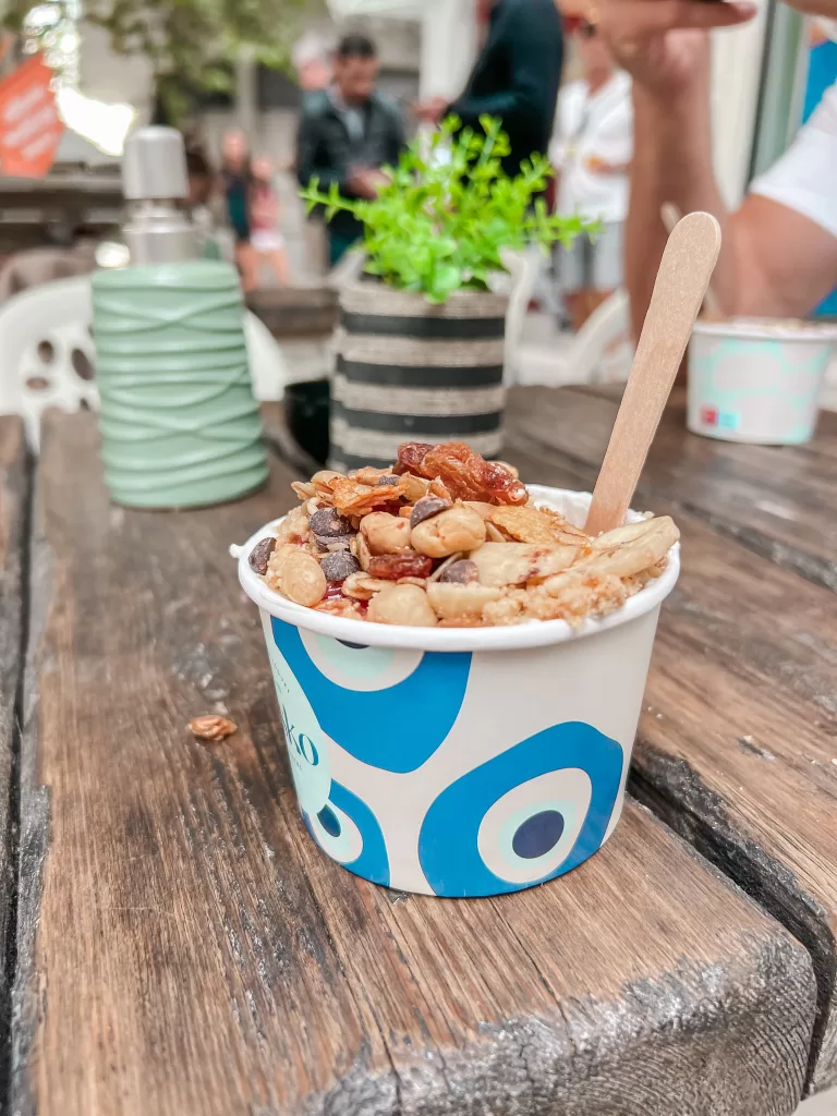 A cup of Greek Yogurt with toppings in an evil eye container